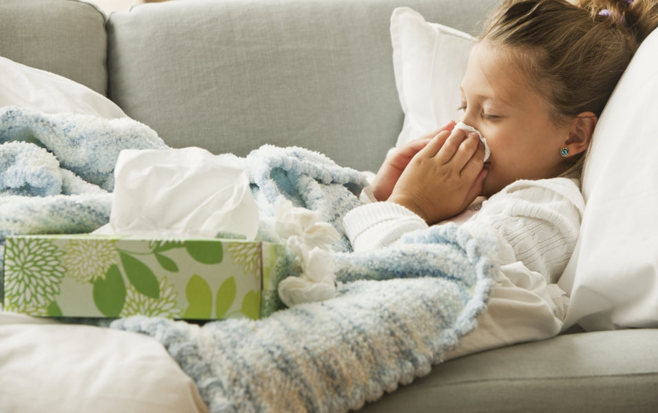 A girl lying on sofa and covering her nose with napkin while sneezing